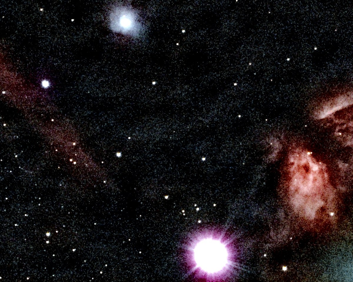 The Flame Nebula's glowing gas and dark dust lane near Alnitak, with the Horsehead Nebula's dark notch visible in the dust lane.