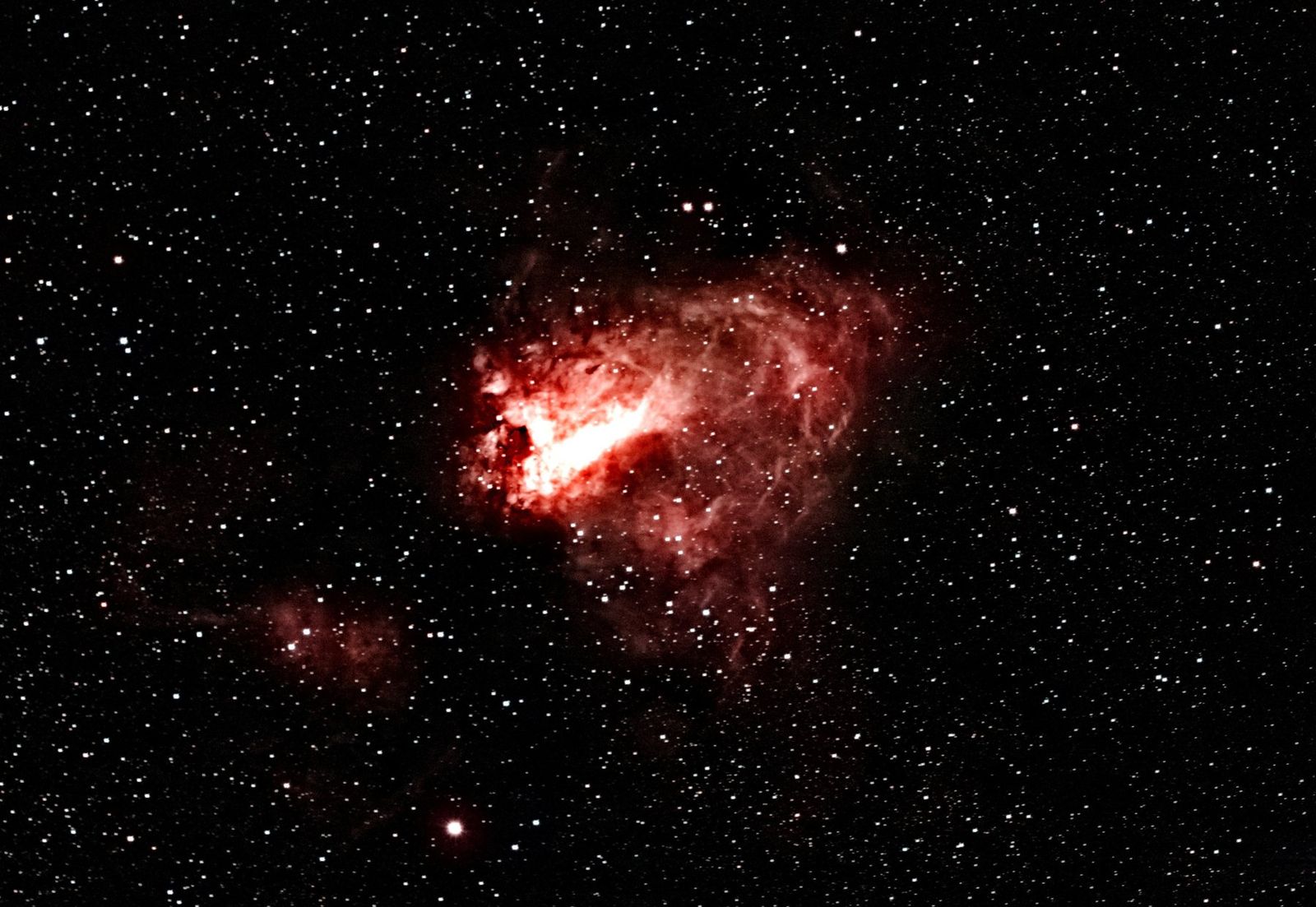 The Omega Nebula after stacking 114 frames and processing: bright red gas with dark lanes against a dense star field.